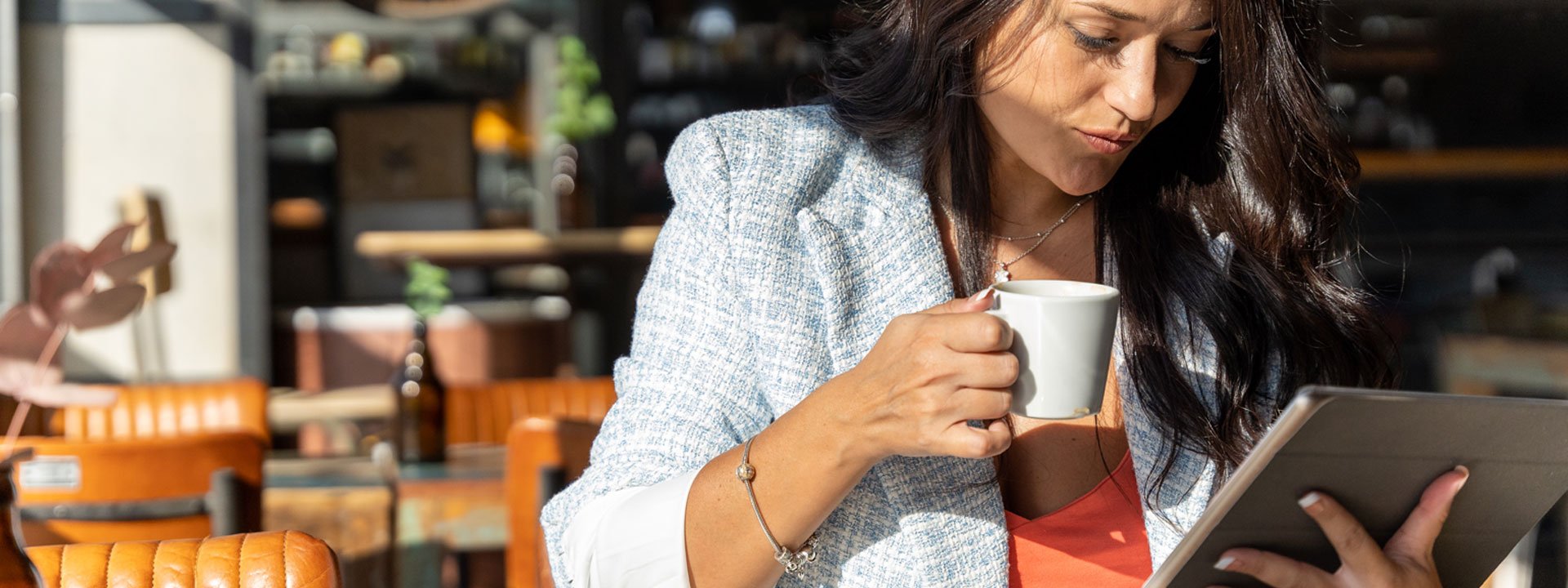 Woman reading news on a tablet in a cafe