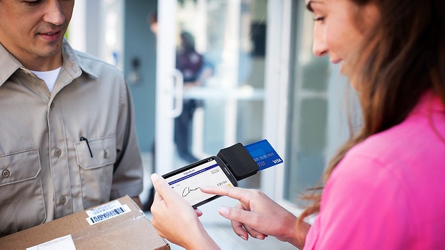 Ouvrir la voie aux points de vente mobiles Woman signing for package using Square Reader on smart phone with her Visa card for payment.