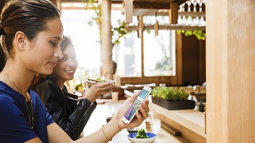 Solutions numériques Visa Two women looking at mobile phone while at lunch.