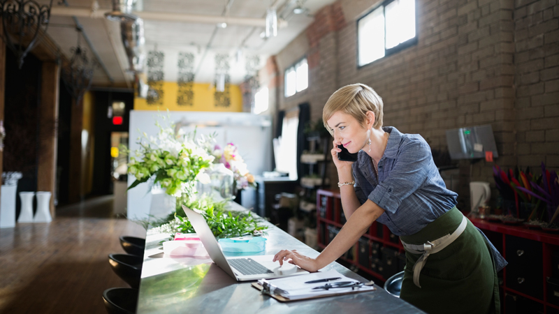 Contactless terminal at a store Florist working on a laptop in flower shop.