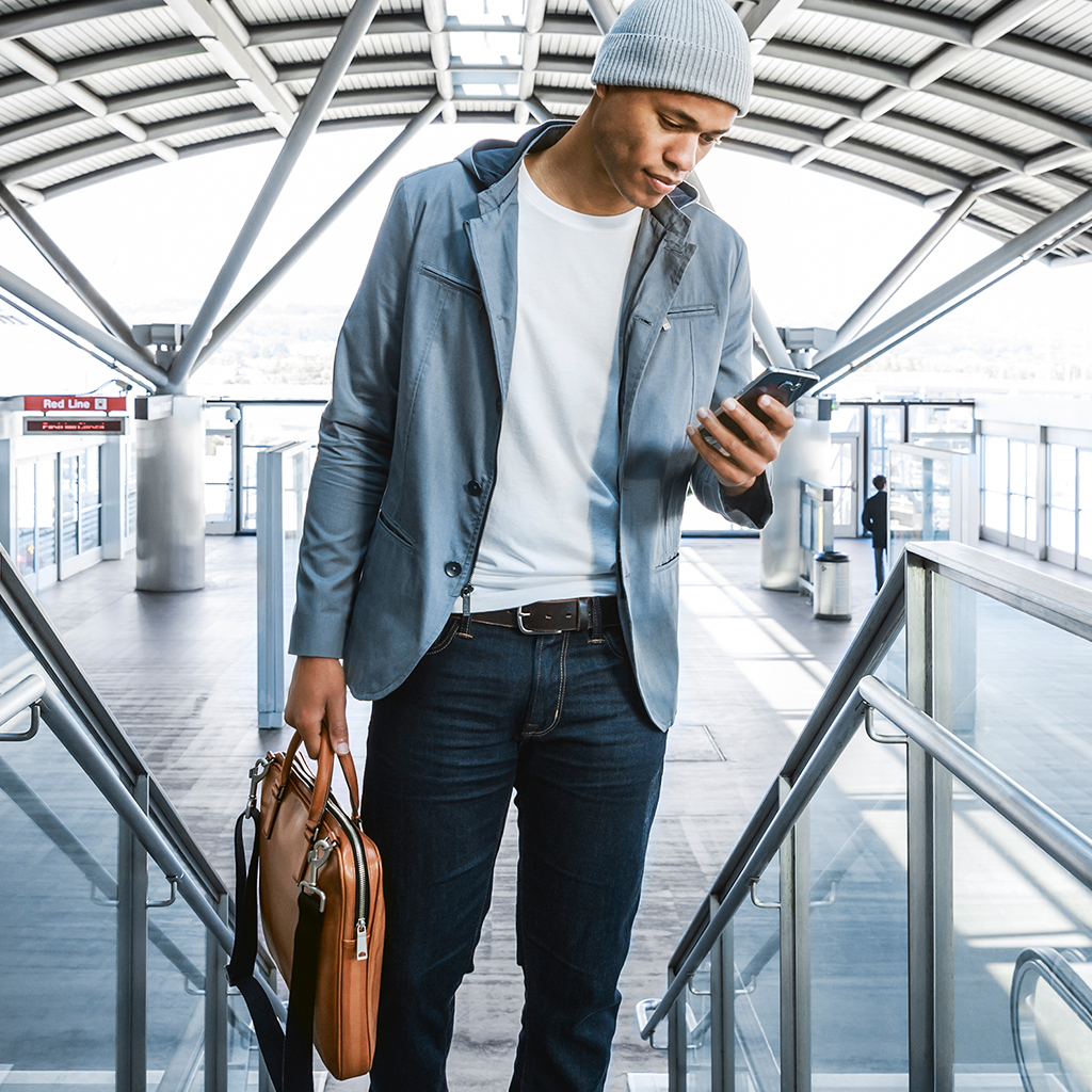 Un homme regardant un téléphone intelligent sur l’escalier roulant d’un aéroport
