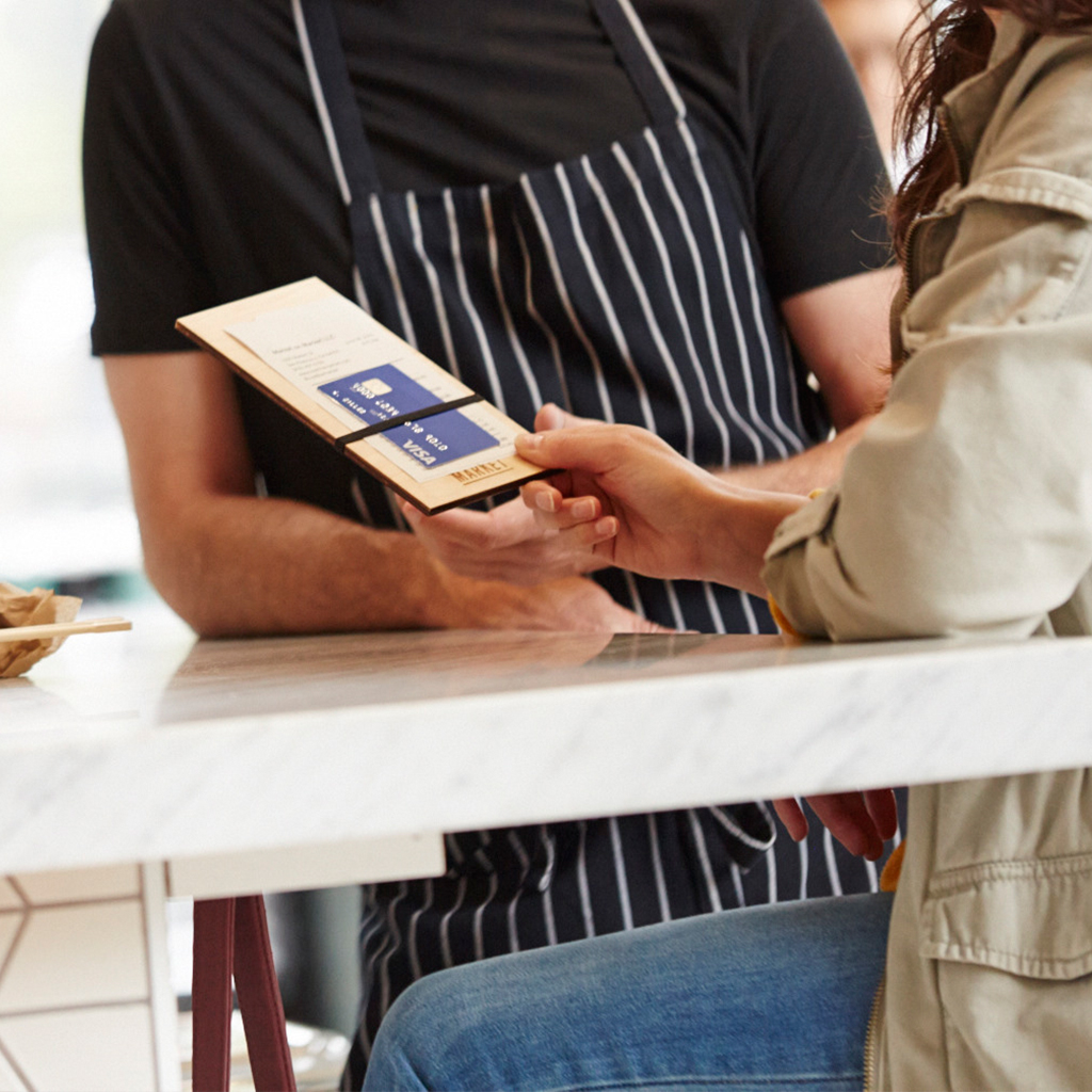 Un client tendant sa carte Visa à un serveur