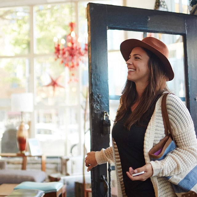 Une femme qui entre dans un magasin, un téléphone intelligent à main.