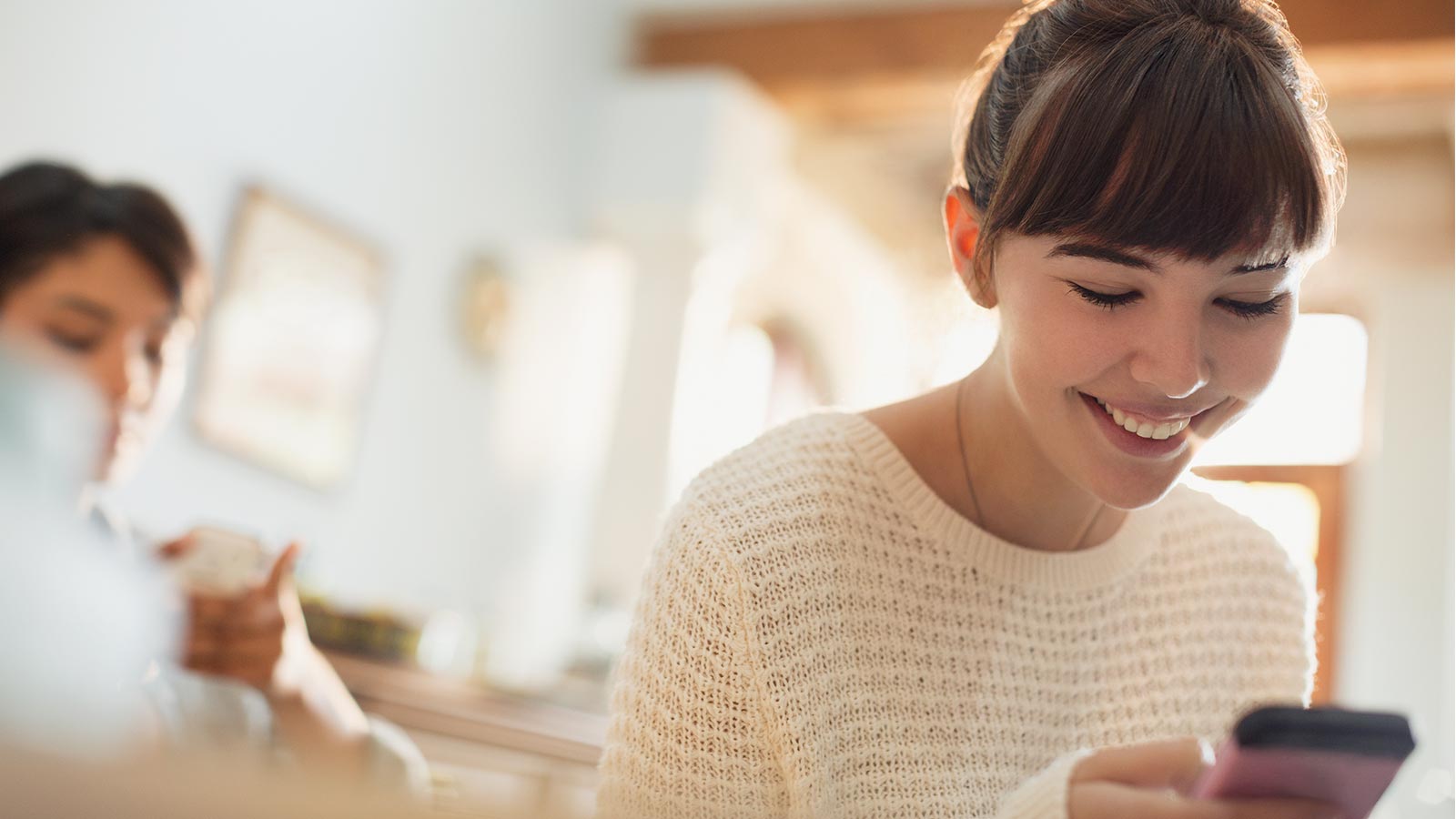 Woman smiling at her phone and making a payment on her device. 