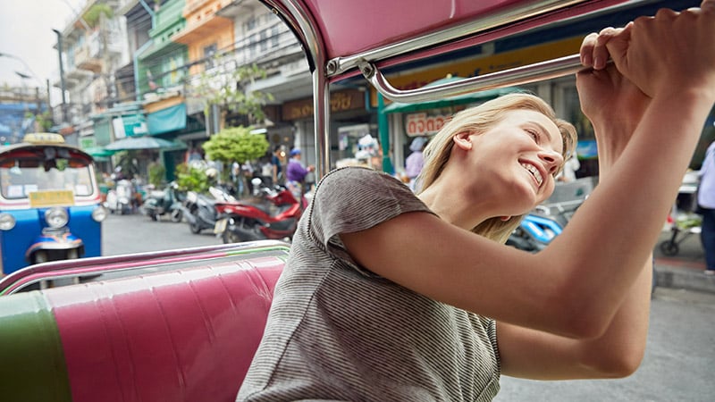 Une femme qui passe la tête par la fenêtre de la voiture en souriant.