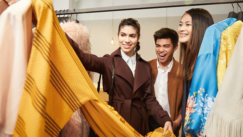 Une femme tenant une chemise dans un magasin pour montrer à ses amis.