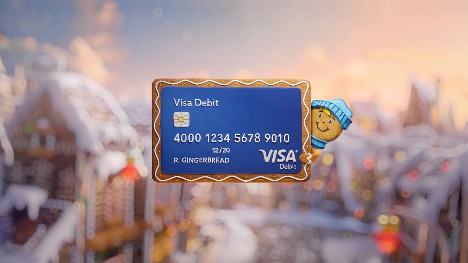Visa ECommerce Campaign Header Visa debit card floating in front of a winter scene being held by a gingerbread man.