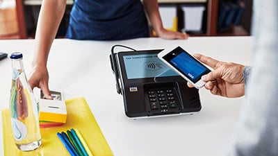 A person makes a payment using their Visa card with a cellphone.