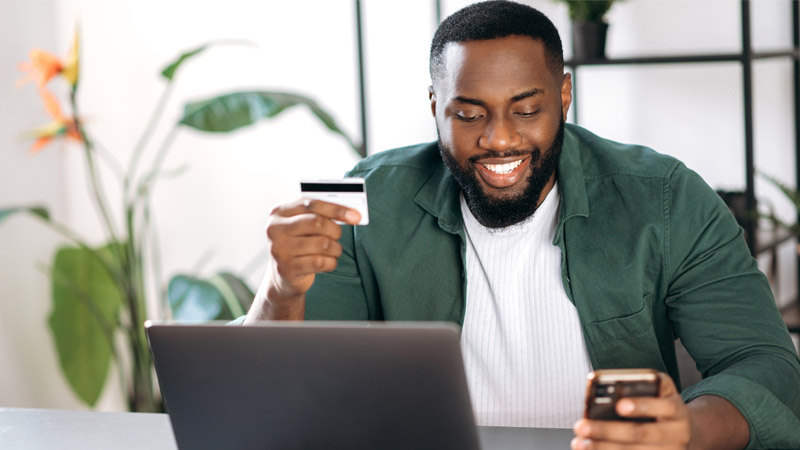 Man looking at phone in front of computer