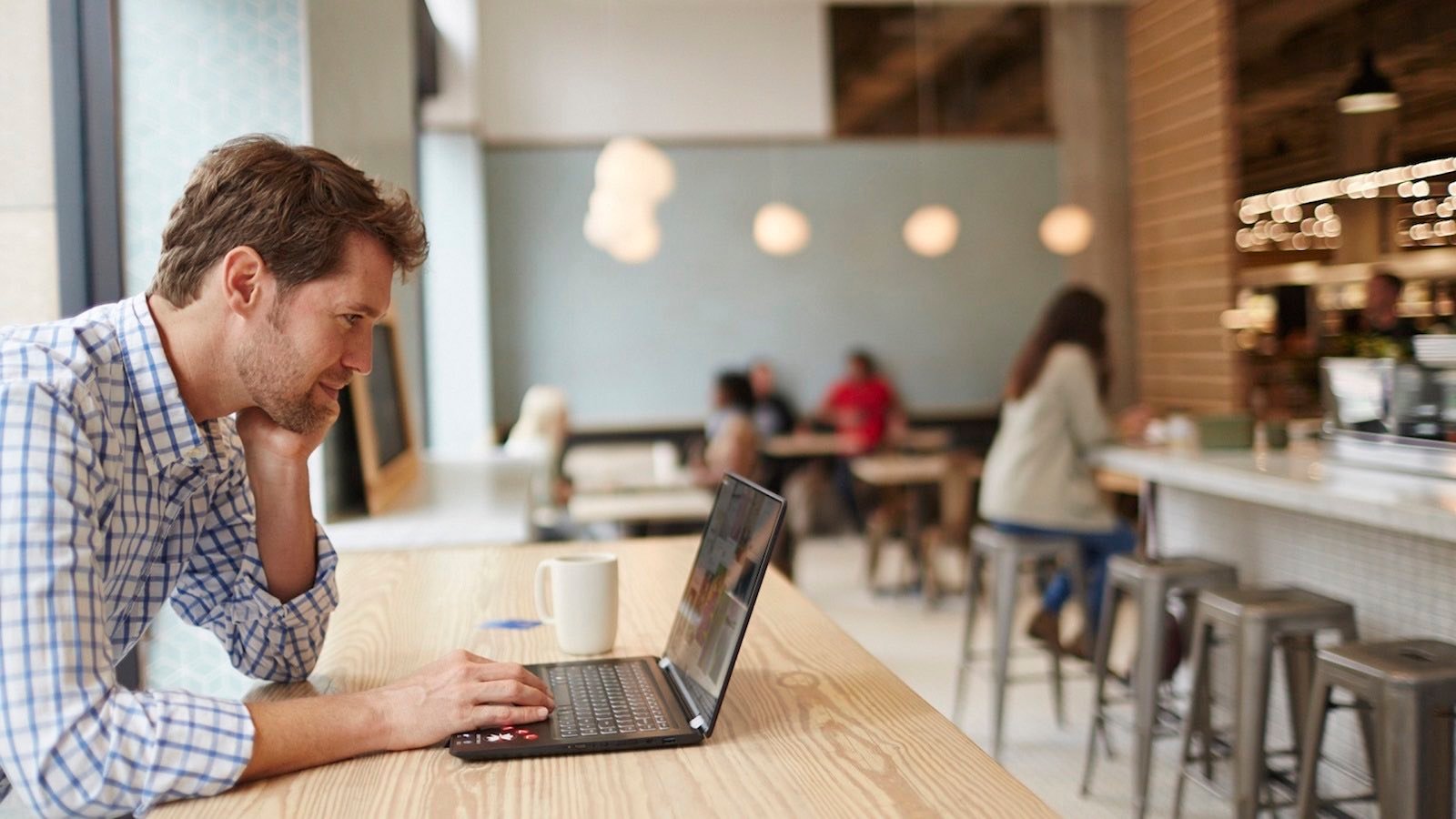 Man viewing his laptop at cafe while having coffee.