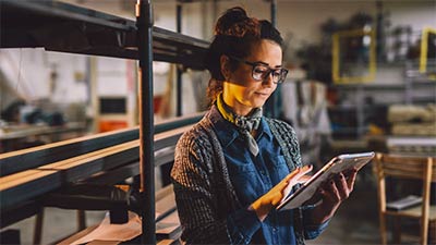 A woman wearing glasses using an iPad to review details about her business.